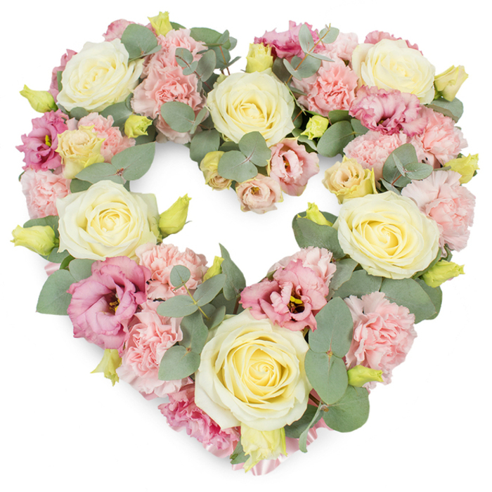 A serene, heart-shaped floral tribute dominates the image, set against a spotless white background that highlights every nuance of its pastel colour palette. The heart is beautifully symmetrical and densely filled, creating an impression of richness and steady, unwavering affection. At its core, pale yellow to creamy ivory roses are spaced throughout the design, each blossom opening in tight yet elegant spirals that feel both luxurious and comforting. These roses act like anchor points in the composition, drawing the eye across the curve of the heart. Surrounding and surrounding them, clusters of softly ruffled light pink carnations introduce a gentle, cloud-like texture, their frilly petals forming a delicate contrast to the smooth rose petals. Deeper tones appear in the form of magenta and mauve-pink lisianthus, their open, trumpet-like flowers and slightly darker centers bringing subtle drama and depth, much like the changing skies over Woodside in late afternoon. Interwoven among the blooms, sprigs of round, silvery-green eucalyptus leaves peek through, lending a cool, calming undertone and enhancing the natural elegance of the design. Tiny yellowish-green buds punctuate the arrangement with hints of new life, reinforcing the idea of remembrance gently entwined with renewal. The overall mood is one of tender condolence and dignified love, suitable for a funeral, memorial, or special anniversary of a loved one. One can easily imagine this wreath placed at a service in Woodside, perhaps delivered to a local church or funeral home, where its quiet beauty and soft fragrance offer solace to grieving hearts. Created with the precision and empathy of an experienced local florist, this heart-shaped wreath becomes a visual expression of everything that is difficult to say aloud in moments of loss.