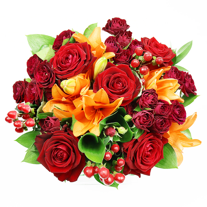 Seen straight down against a pure white backdrop, this opulent, circular bouquet presents a rich tapestry of reds, oranges and greens arranged with confident floral technique. Several large, fully blooming deep-red roses command attention at the centre, their velour-like petals layered into perfect, romantic spirals that suggest enduring affection. Accent orange Asiatic lilies intersperse vibrantly-some flaring fully open with dark-speckled throats and prominent stamens, others held in sleek buds-creating a pleasing rhythm of shapes that lead the eye around the composition. Surrounding and cushioning the main blooms are tight clusters of dark burgundy spray roses whose tiny, complex blooms intensify the colour depth and offer a plush contrast in scale. Small clusters of glossy crimson hypericum berries add lively punctuation and a tactile brightness, while broad green leaves-likely ruscus or salal-peek between flowers to provide cool relief and structural support. The arrangement is densely packed but airy where it needs to be, a balance that reflects thoughtful conditioning and placement of each stem under soft, even lighting that preserves true colour and texture. The visual and imagined scent profile is warm and floral, with the sweetness of rose layered over a lily's crisp, slightly spicy lift. A bouquet like this reads as celebratory and tender, suitable for anniversaries, autumnal events or thoughtful gifts. It evokes local occasions such as community gatherings near Woodside's shops and parks, and mirrors the kind of bouquet we prepare for same-day neighbourhood deliveries with careful attention to seasonal freshness and presentation.